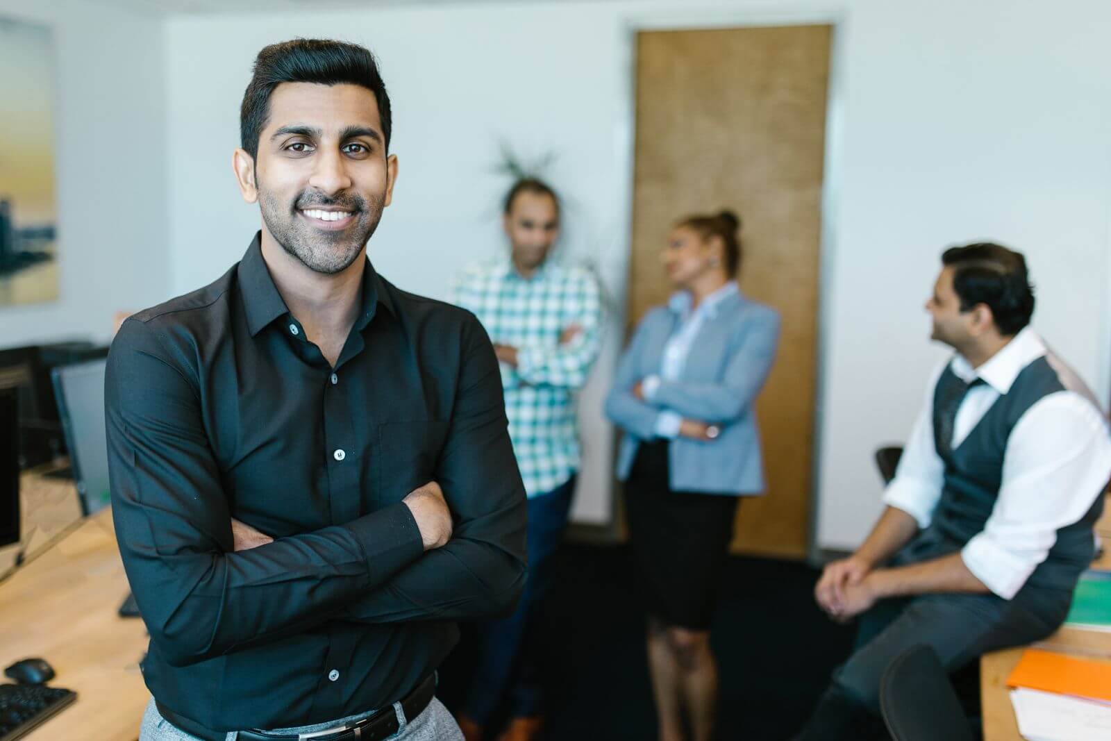 Smiling Indian technology leader with colleagues in a modern office