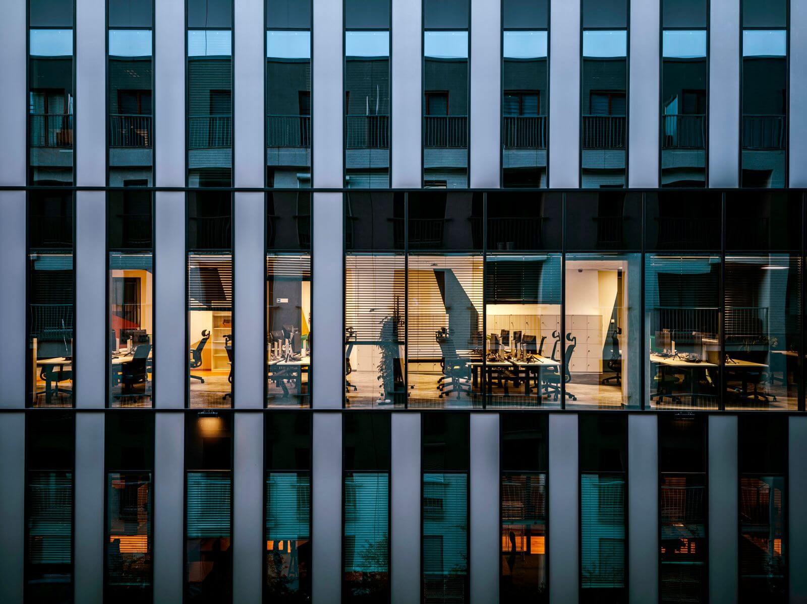 Illuminated offices visible through a modern glass building